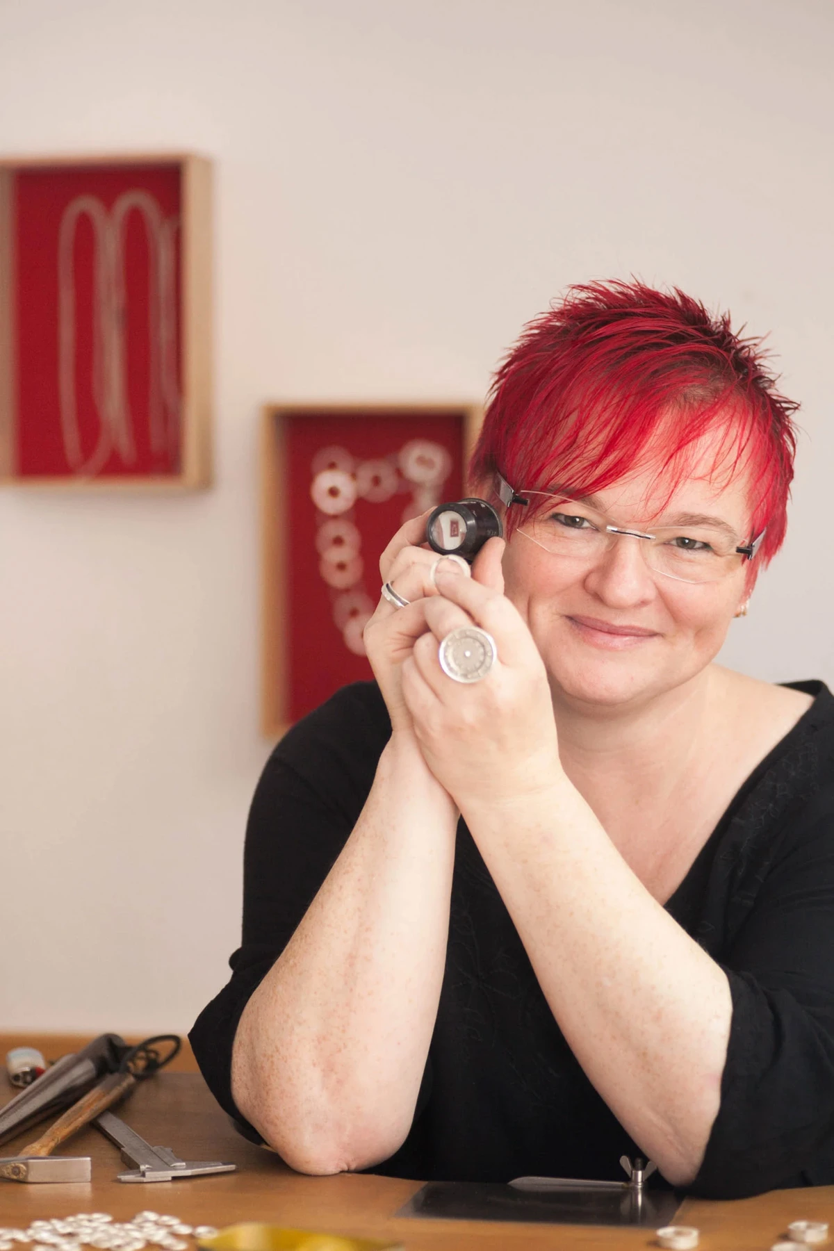 Portrait der Gold- und Silberschmiedemeisterin Silke Jüngst in ihrer Werkstatt, mit einem Schmuckstück in der Hand.